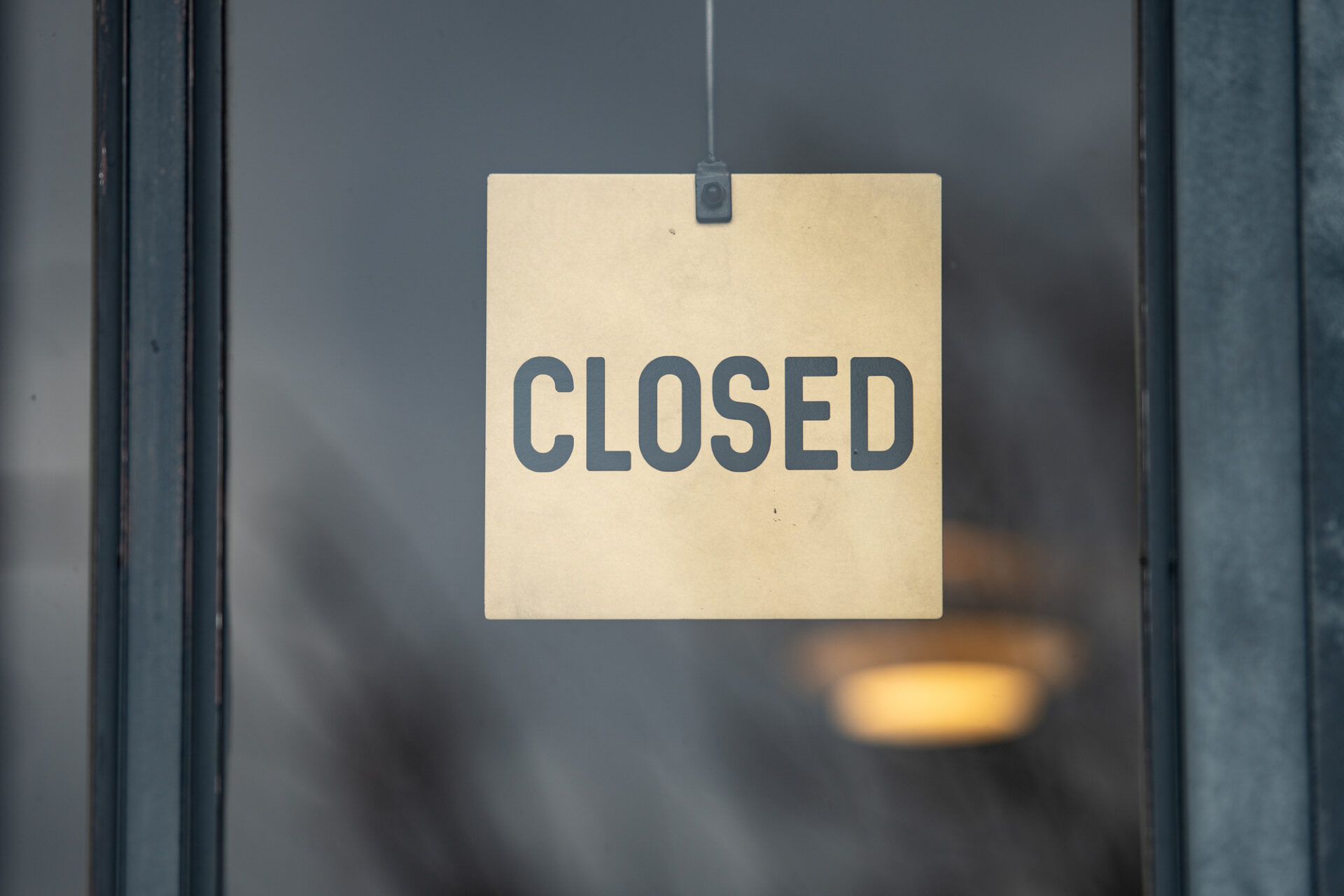 「CLOSED」の看板が窓の外に掲げられている
