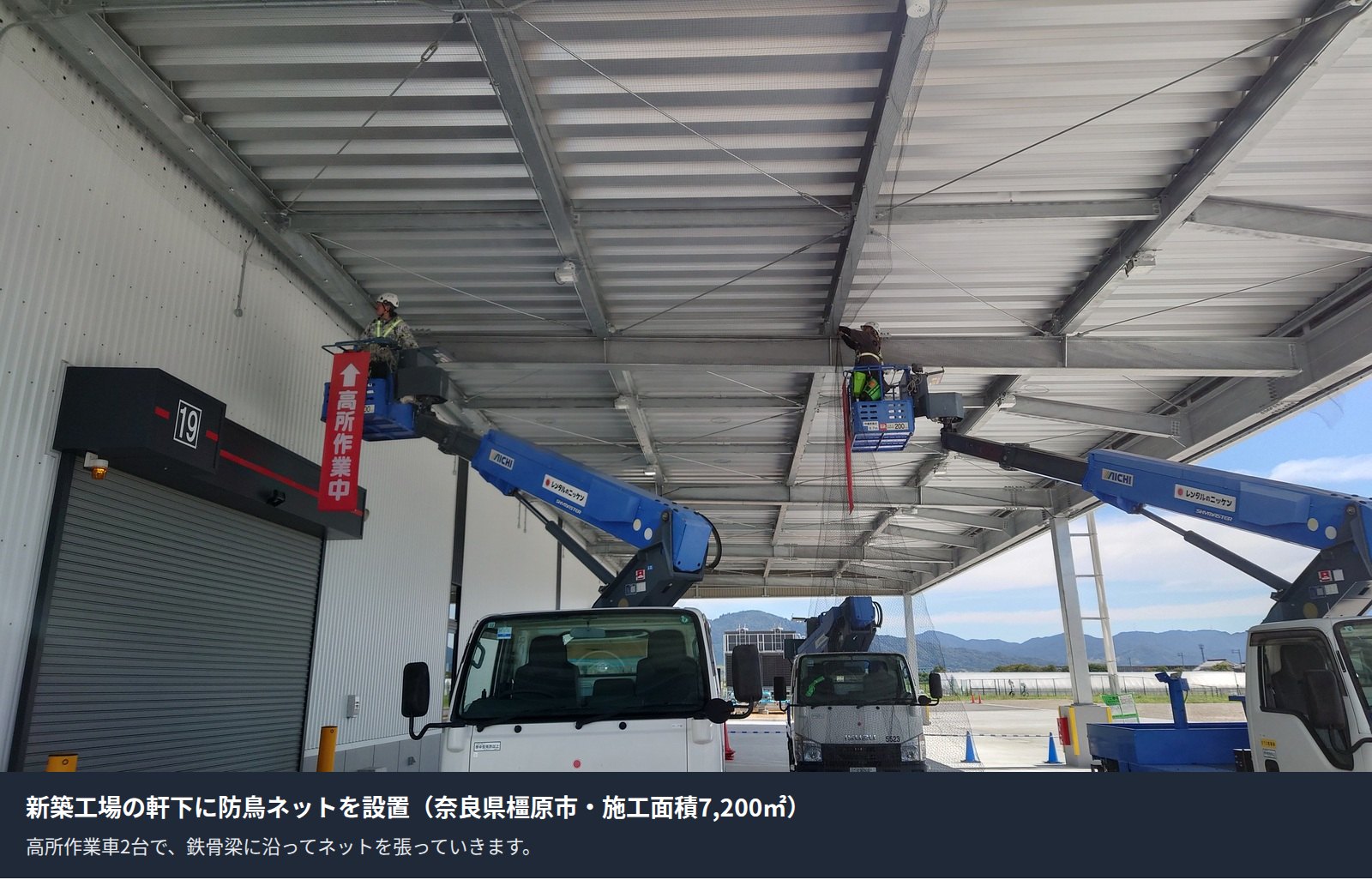 新築工場の軒下に高所作業車2台で防鳥ネットを設置している様子(奈良県橿原市)